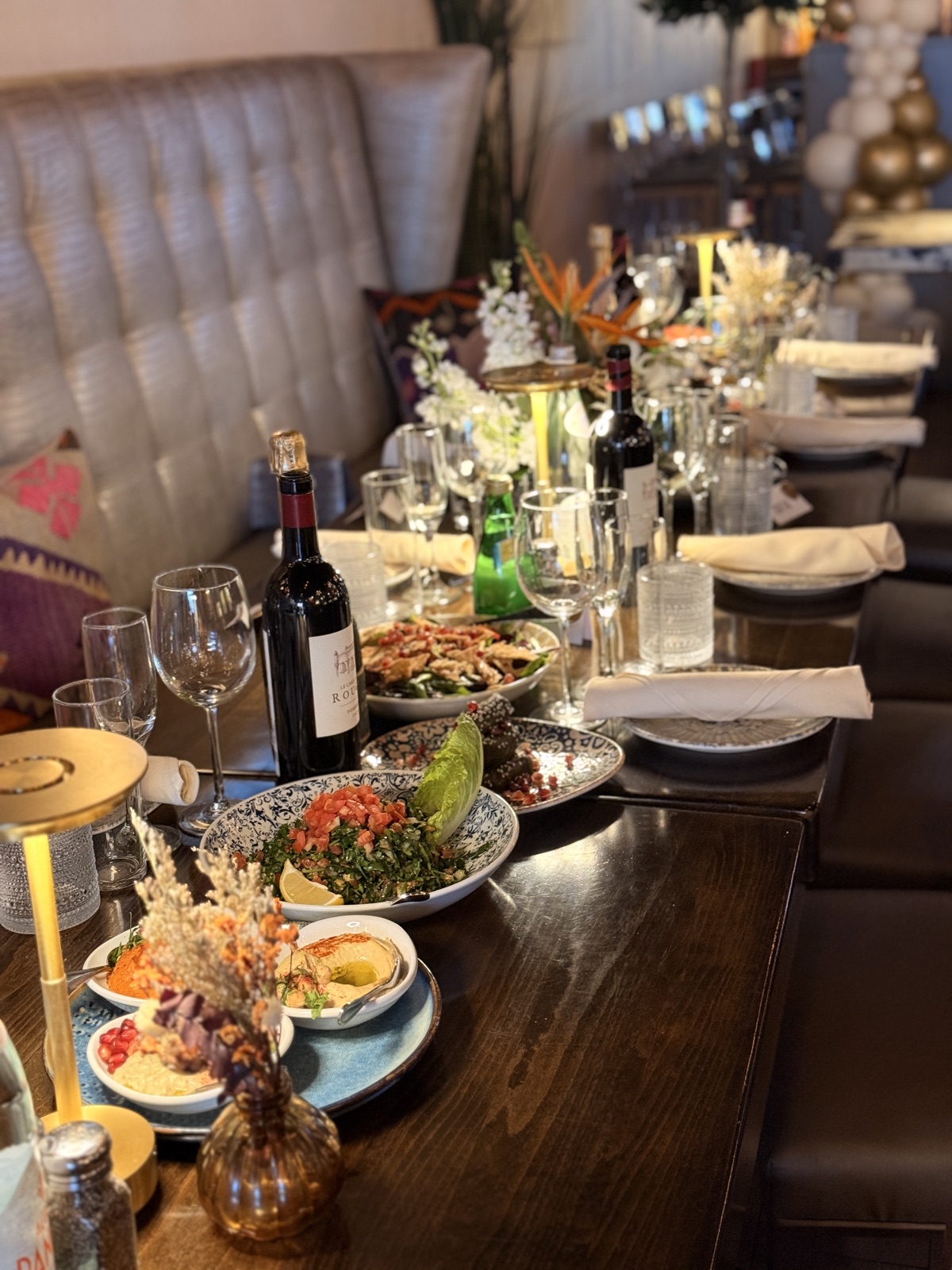 Long table at Mezzé #1 set with mezze, wine, and lit candles before guests arrive